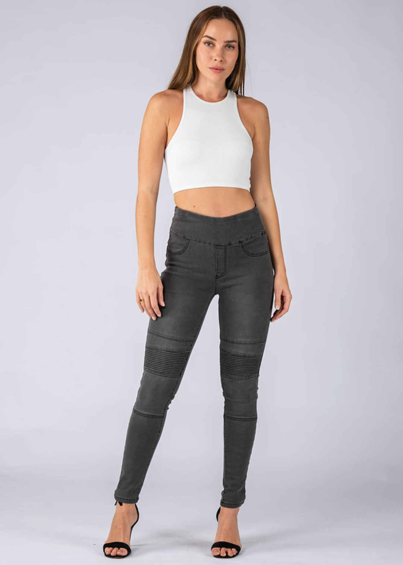 Woman wearing black pants and a white top on a plain background