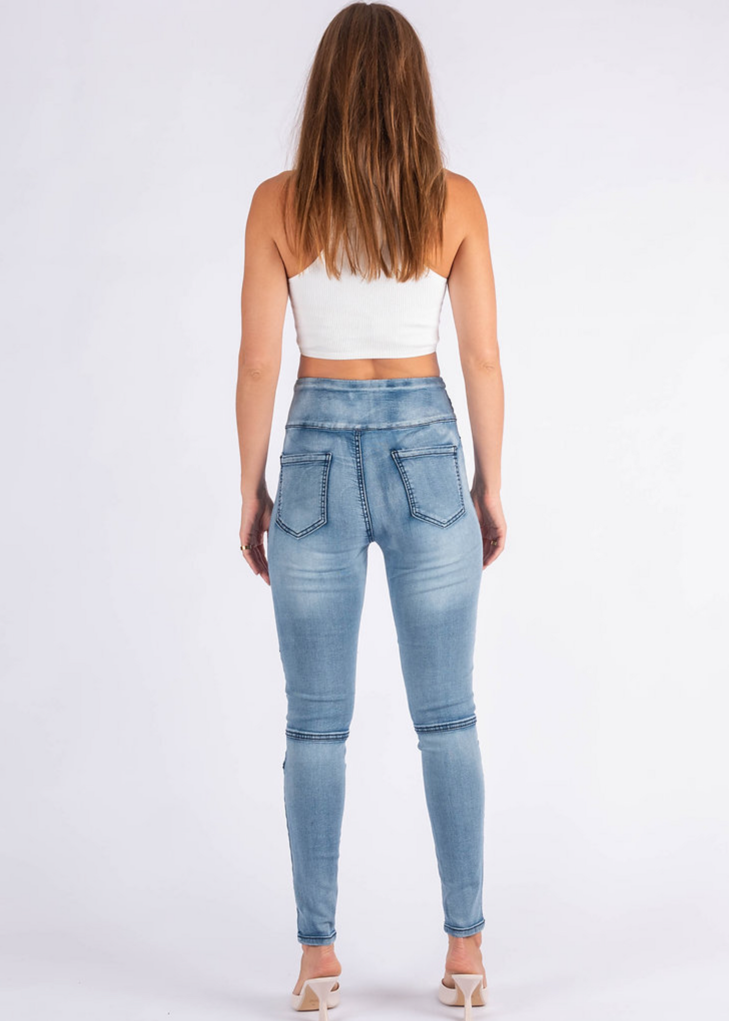 Woman wearing light blue jeans on a white background