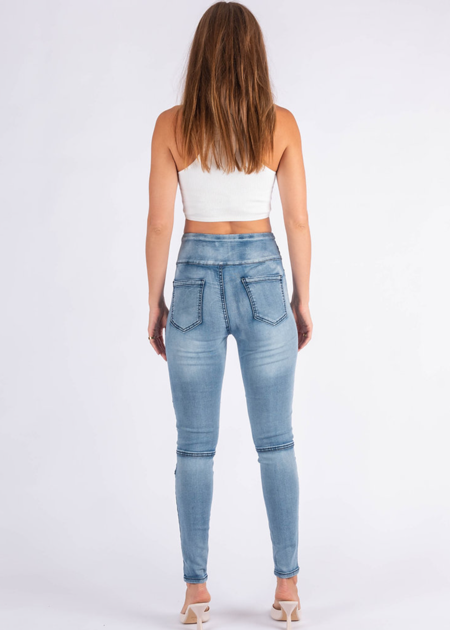 Woman wearing light blue jeans on a white background