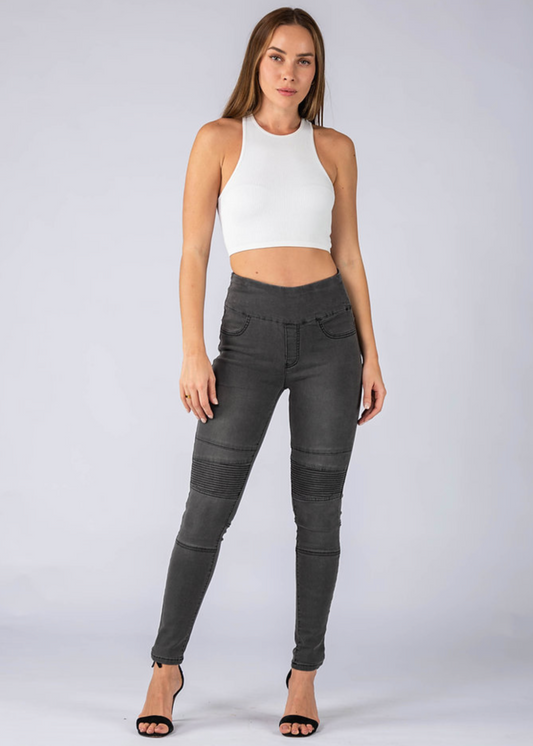 Woman wearing black pants and a white top on a plain background